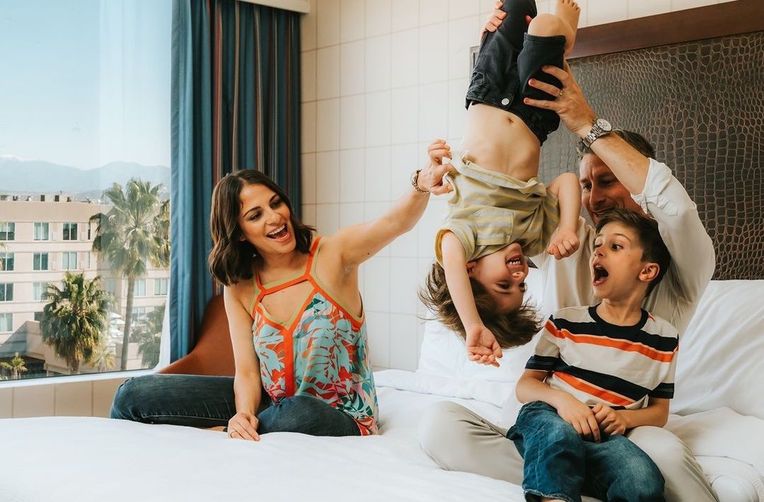 Family playing on hotel bed